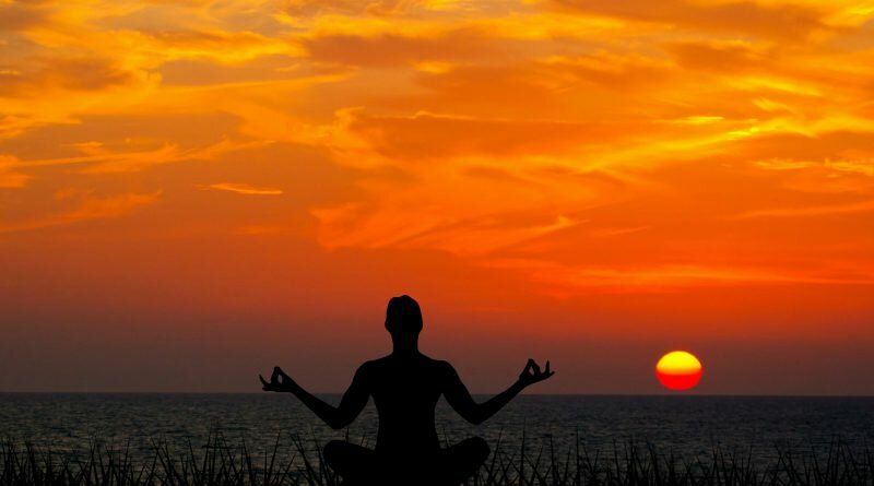 Homem meditando no pôr do sol